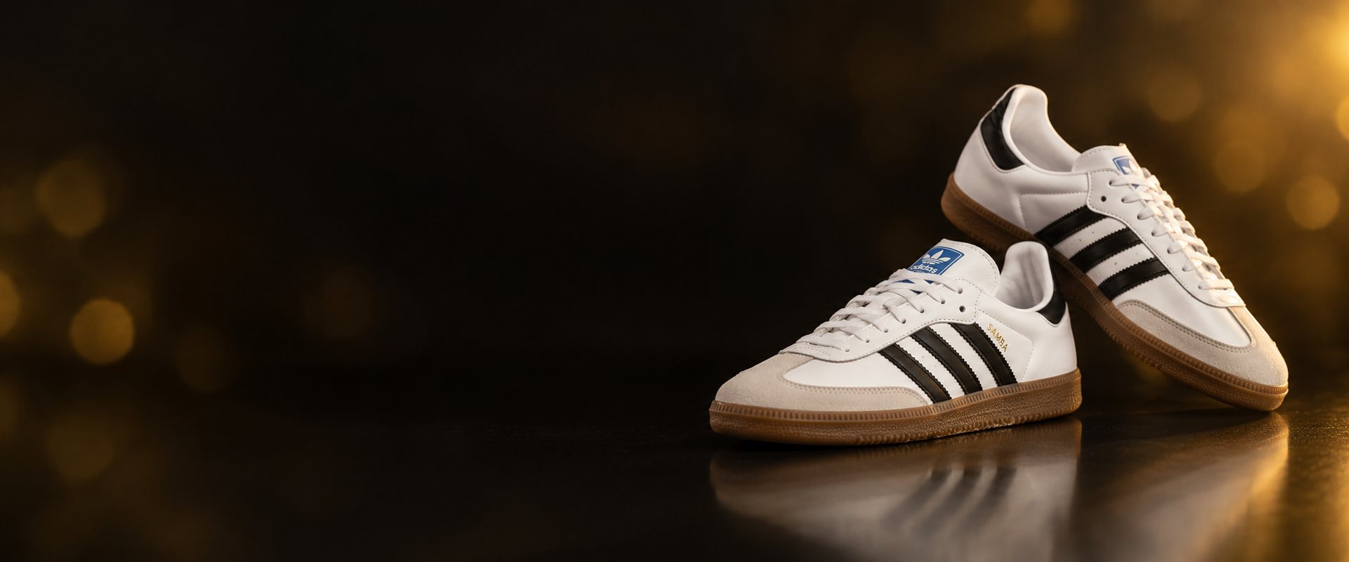 Par de Adidas Samba brancas com riscas pretas e sola de borracha, sobre fundo escuro